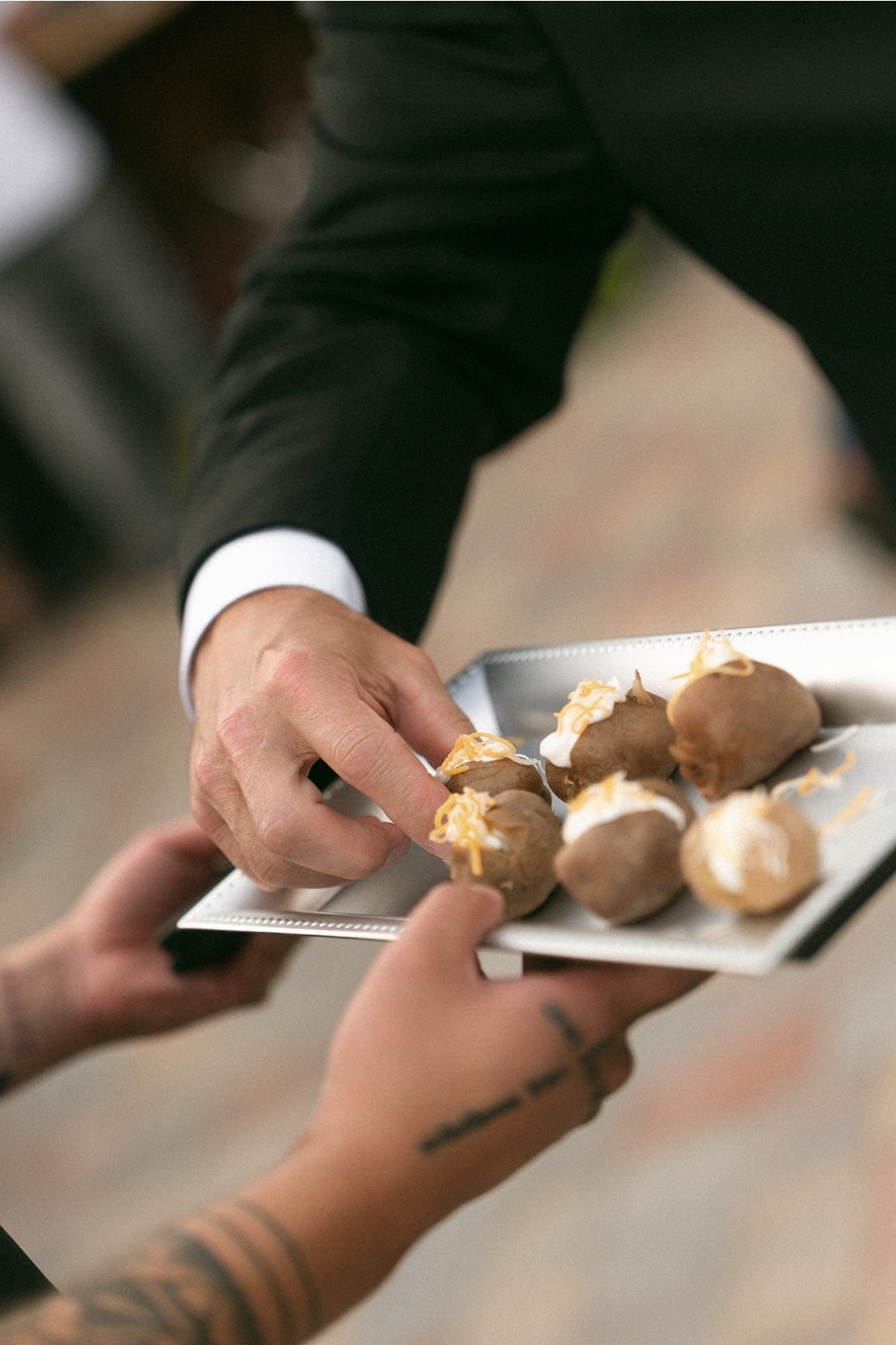 Server passing mini baked potato hors d'oeuvres