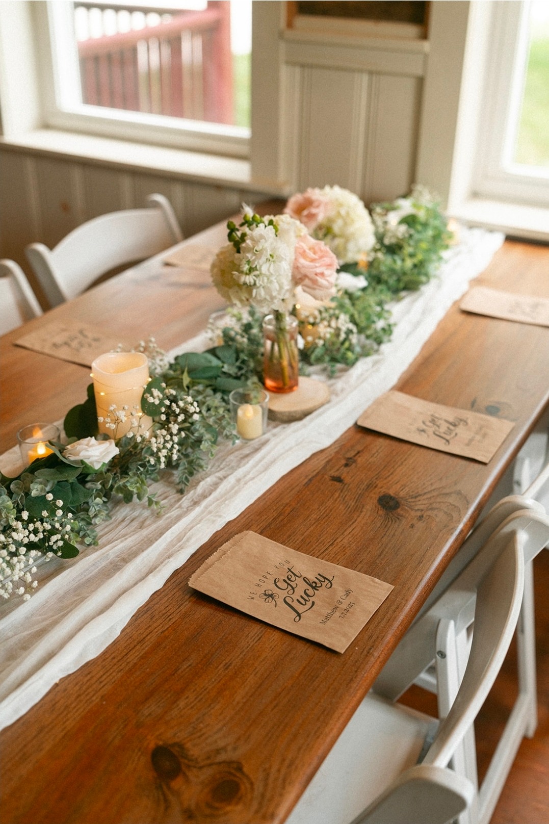 Farm table with greenery garland, candles, and favor bags